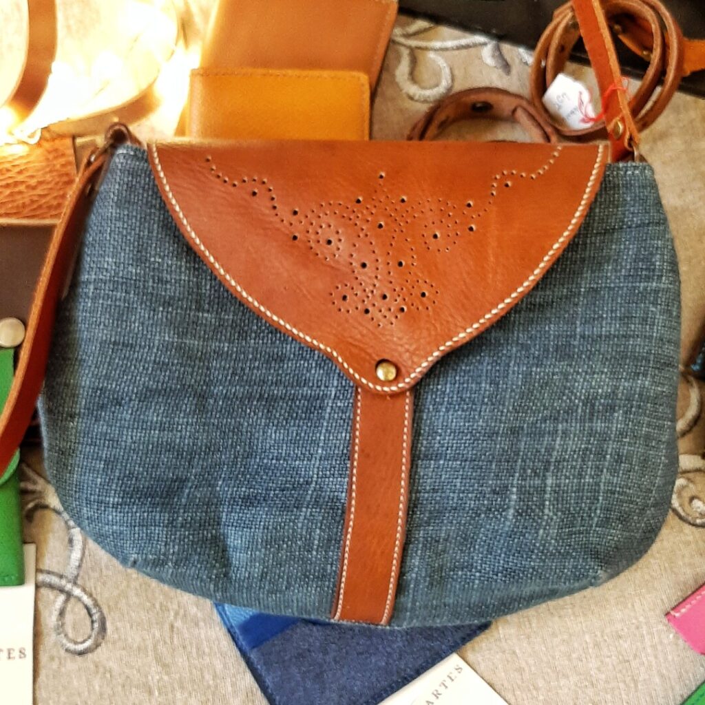 sac en lin bleu et son rabat en cuir orné d'un motif perforé à la main