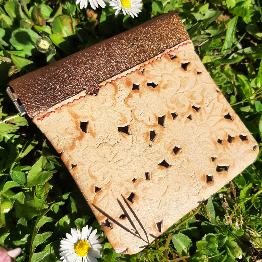 Porte monnaie clac clac en cuir gaufré de fleurs et ajouré, et son bord en cuir vieil or métallisé. Un charme fou pour ce porte-monnaie, bien pratique avec sa fermeture à cliquet qui fait clac ! Couture au point sellier avec un fil de lin cuivré