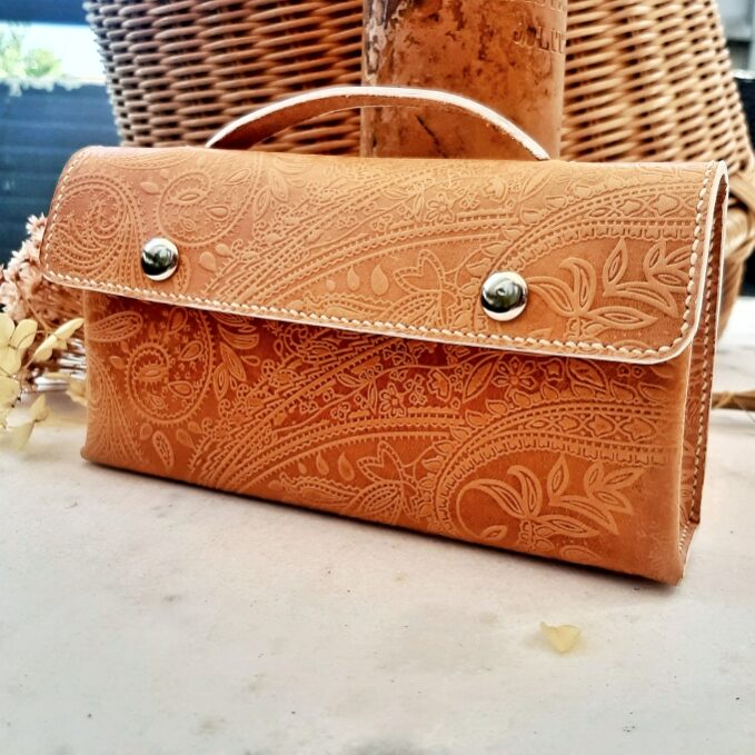 Petite pochette en cuir naturel tannage végétal avec motifs cachemire gaufré. Cousu main au point sellier avec fils de lin de couleur blanc cassé. Petite poignée. Finition des tranches en blanc. Fermeture du rabat par 2 boutons magnétiques métal argent.