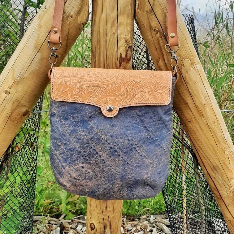 Sac bandoulière de la collection Myrlande. Cuir de chèvre fantaisie effet vieilli et couleur jean. Rabat cuir naturel tannage végétal motif cachemire gaufré dessus. Bouton couleur canon de fusil magnétique. Couture main au point sellier. Bandoulière réglable et amovible grâce à ses mousquetons en cuir naturel tannage végétal. Couture main au point sellier avec fil de lin bleu.