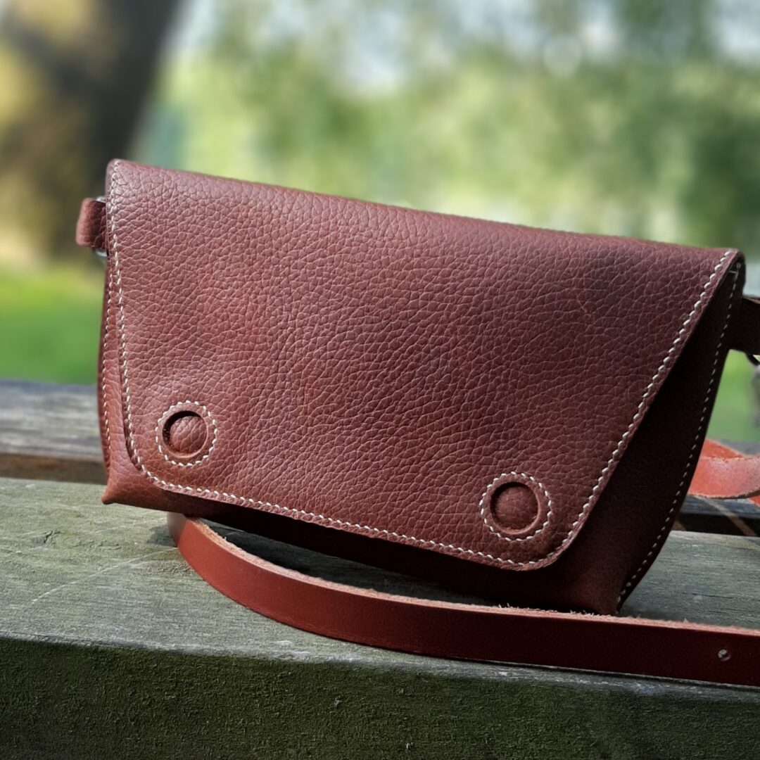 Petit sac en cuir grainé marron pull up. Couture main au point sellier. Rabat muni de 2 boutons magnétique pour sa fermeture.