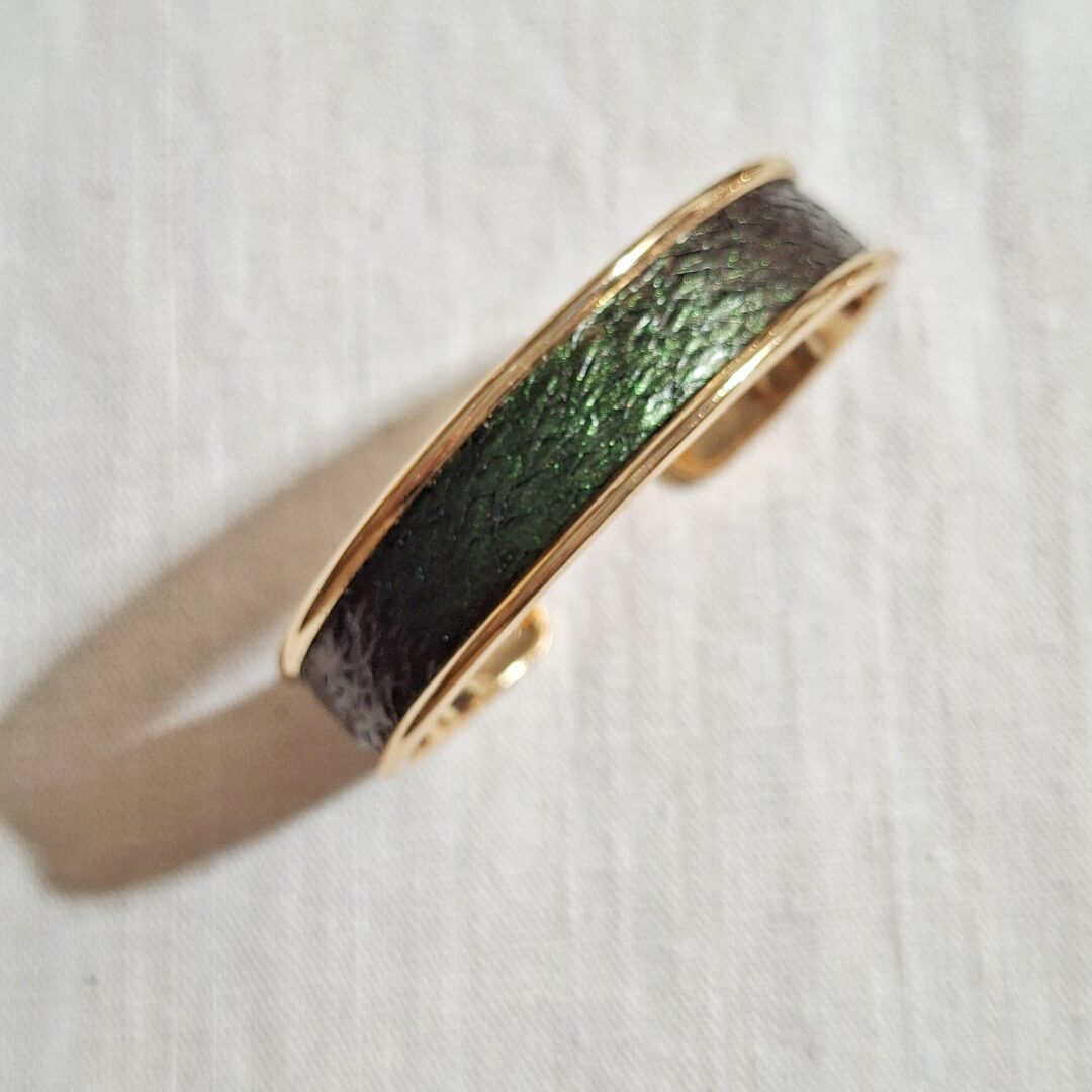 bracelet manchette en laiton doré avec cuir de saumon vert foncé aux reflets irisés.