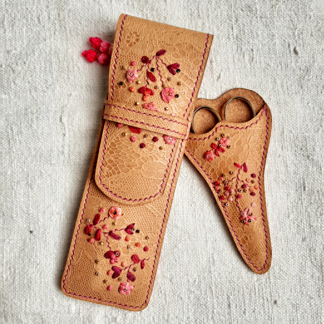 Etui à crochets en cuir tannage végétal embossé d'un motif dentelle. Brodé main de motifs fleuris, et cousu main au point sellier avec un fil de lin fuchsia.