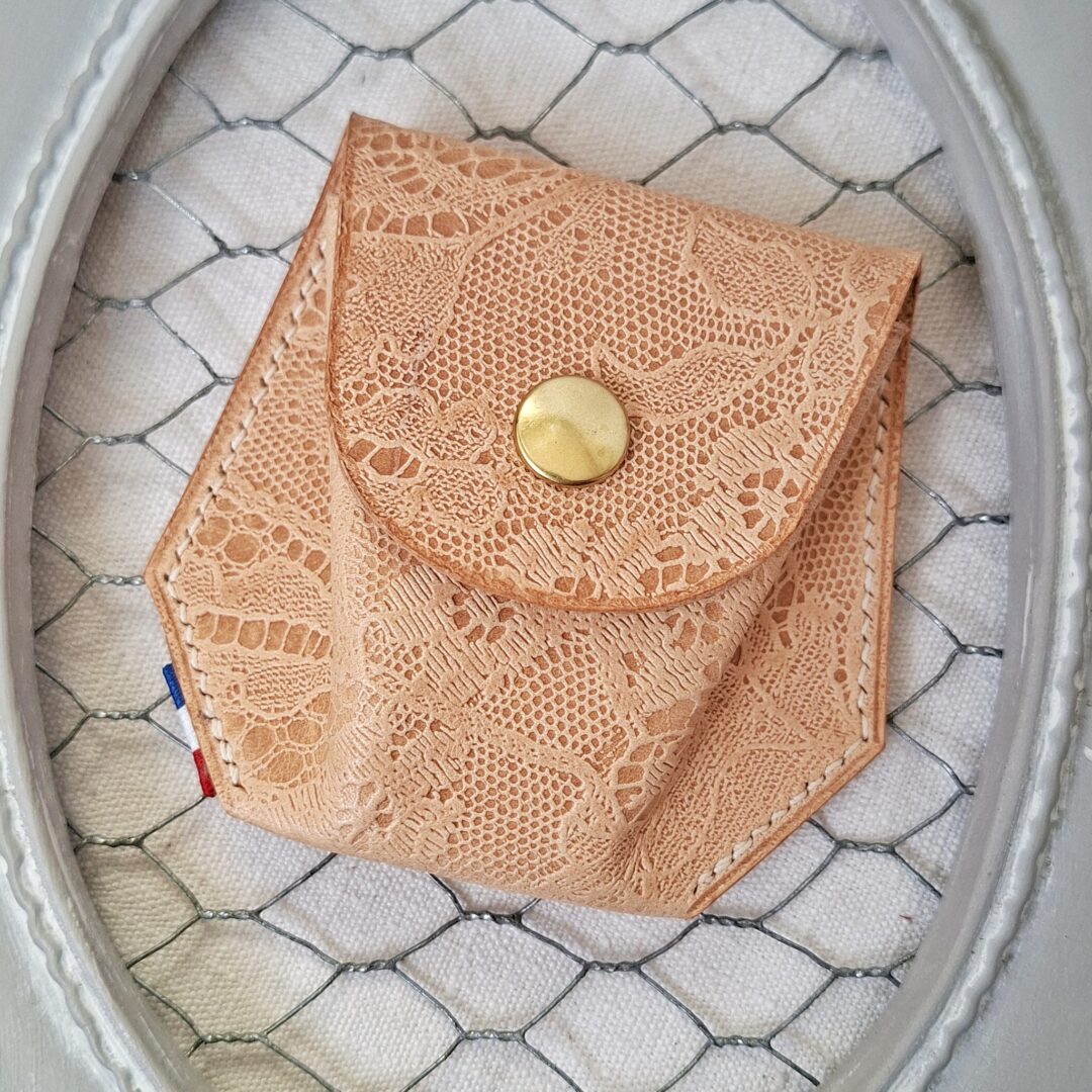 porte monnaie dans un cuir tannage végétal de couleur naturel et embossé d'un motif dentelle, de forme hexagonale. Bouton pression doré, cousu au point sellier au fil de lin crème.