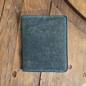 Porte-cartes en cuir bleu turquoise foncé fermé sur table en bois
