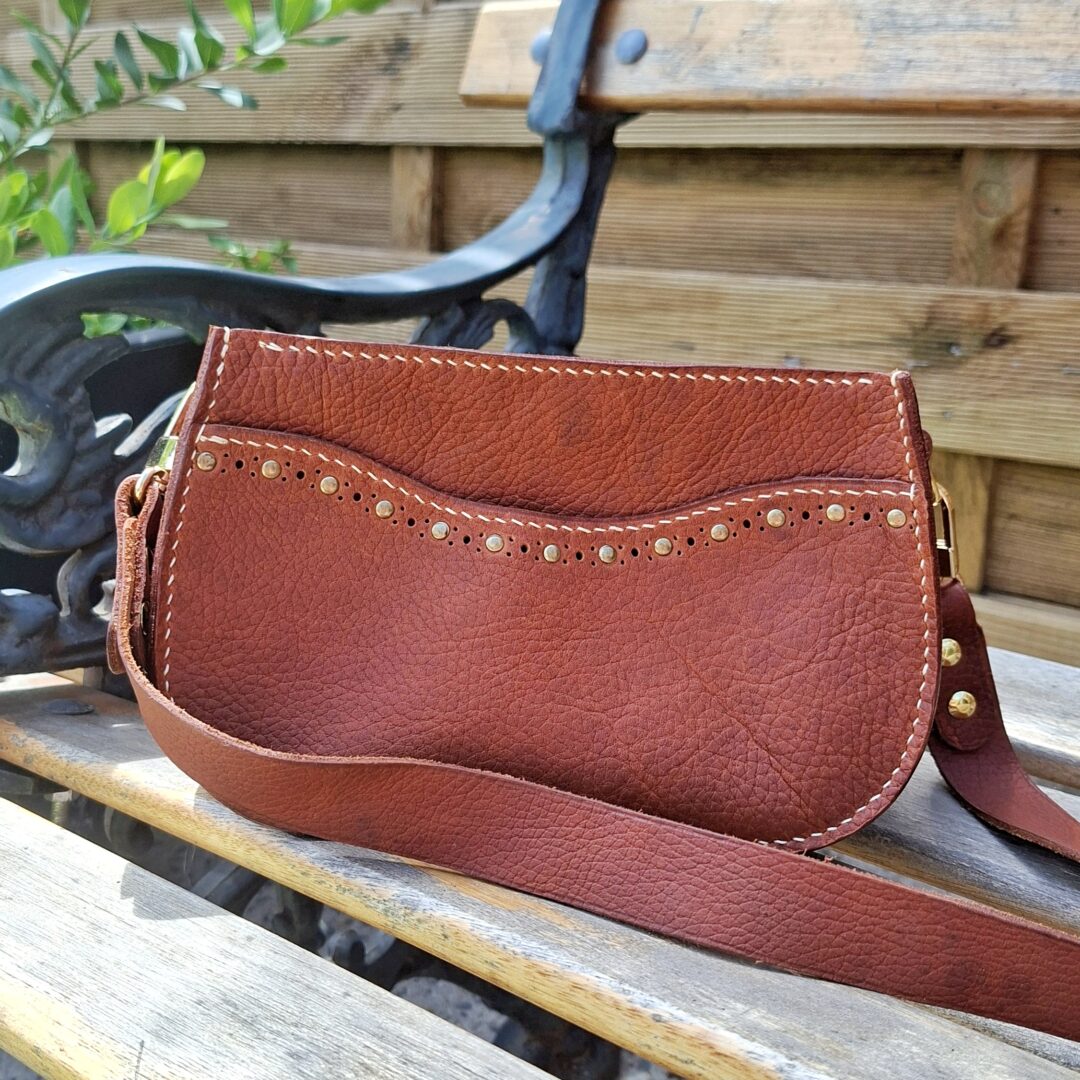 Sac porté épaule artisanal en cuir grainé pull-up marron chaud avec poche avant décorée de rivets et frise perforée.