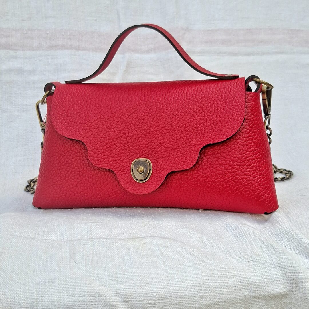 Sac bandoulière en cuir pleine fleur rouge framboise avec rabat ondulé, poignée et fermoir en laiton vieilli, fabrication artisanale française.