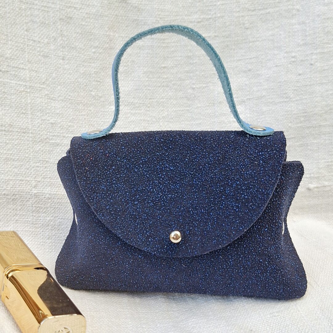 Petit sac en cuir bleu nuit pailleté fait main avec poignée en cuir pleine fleur bleu azur et fermeture à bouton de col.