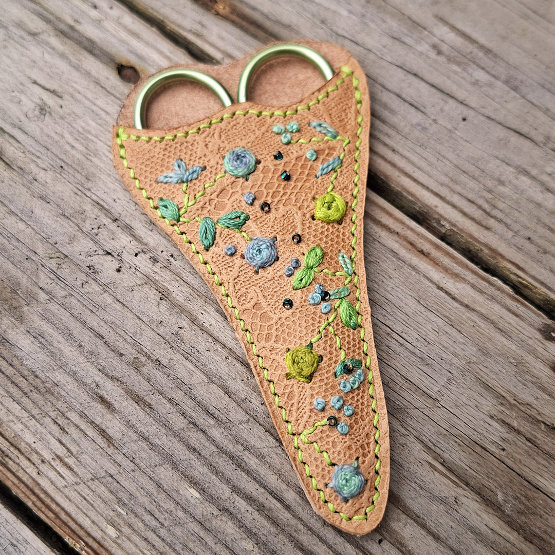 Étui à ciseaux de broderie en cuir tannage végétal embossé motif dentelle, brodé à la main de fleurs et feuillages aux cotons dégradés, avec ciseaux assortis
